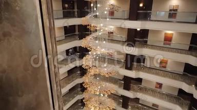 一个昂贵的，美丽的城市酒店，一个金色的螺旋吊灯与电梯在大厅的中心。 从顶端