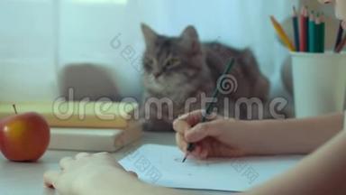 小女孩用<strong>铅笔</strong>和猫坐在她旁边的桌子上<strong>画画</strong>
