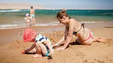 小母亲和她的孩子儿子在<strong>海边玩玩</strong>具车的4k视频。 夏季海滩家庭放松