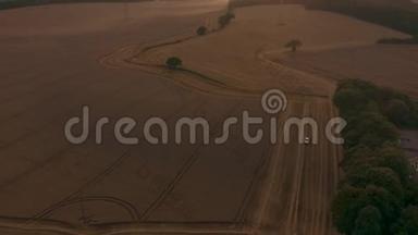 美丽的空中日落在乡村的英国乡村，展现了史诗般的景观远景，农民收割麦田