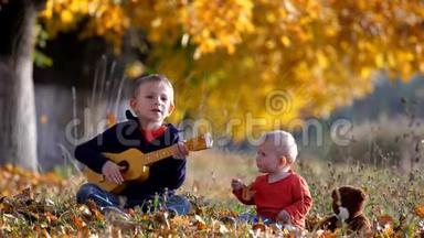 秋天公园里逗乐的孩子用吉他唱歌给小弟弟的画像