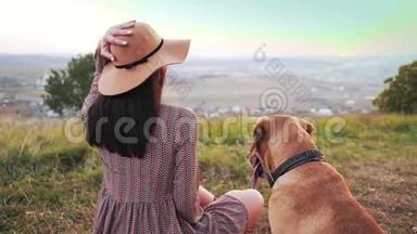 带帽子的<strong>可爱女孩</strong>的后景和她可爱的狗坐在草地上。