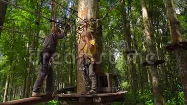 在森林探险公园的树梢上，两个穿着安全带的小男孩在一条路线上爬起来