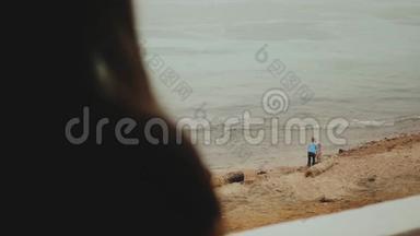 独自一人的女人早上在阳台上喝咖啡或茶，有蓝色的海景，孩子们在海边玩耍