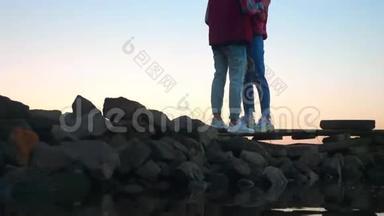 真实拍摄的情侣站在天空背景上的石头上，抱着对方，真爱的氛围，令人惊叹的景色