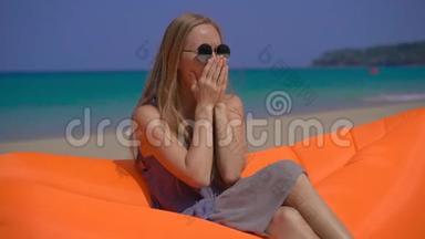 一名年轻<strong>女子坐在</strong>热带海滩上的充气<strong>沙发上</strong>咳嗽时的超慢镜头。 旅行疾病