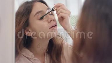 漂亮的女人用睫毛膏做睫毛前浴室镜子