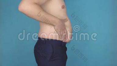 两个男人接触脂肪<strong>堆积</strong>在脂肪<strong>堆积</strong>的肚子上，超重，不健康的饮食，蓝色背景，问题