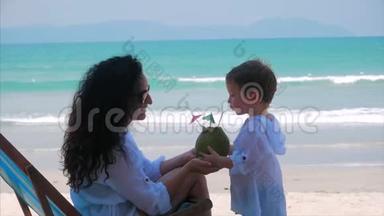 快乐的母亲吃她可爱的小椰子。 有宝宝在户外、家庭幸福、童年快乐的概念妈妈