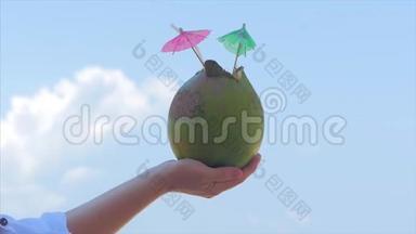年轻<strong>的</strong>双手女人在热带海滩上<strong>的</strong>美丽<strong>的</strong>云彩背景中抱着椰子。 <strong>暑假的</strong>概念