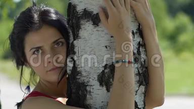 年轻<strong>天真</strong>的女人看着镜头，在户外拥抱一棵树，热爱自然，团结