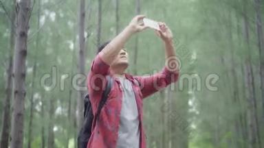 徒步<strong>旅行</strong>者亚洲背包客男子使用智能手机<strong>拍照</strong>时，徒步<strong>旅行</strong>冒险步行森林。