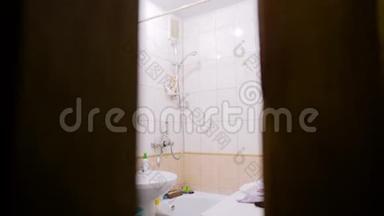 镜头透过浴室里正在发生的事情背后的一扇半开着的门。
