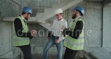 三名建筑师在工作日结束时在工地上跳舞，身穿能见度很高的背心，穿着坚硬的衣服