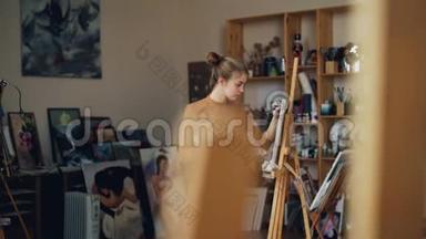 有创意的年轻女士正在画油画，独自站在画架前，画着美丽的油画
