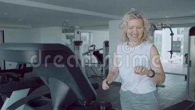 一位老年妇女正在健身房的跑步机上做运动有氧运动钟