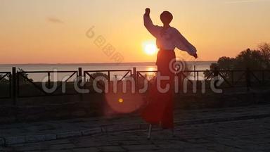 穿着乌克兰西装的男人在夕阳西下的海边踩着高跷跳舞