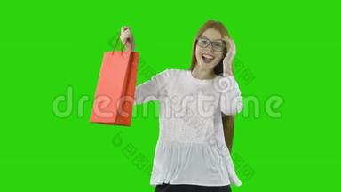 快乐而快乐的女孩带着一个红色的纸袋，在一个孤立的<strong>绿色</strong>背景下在<strong>商场</strong>购物后。