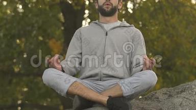 活泼的男人坐在岩石顶部的莲花位置，冥想和放松，爱好