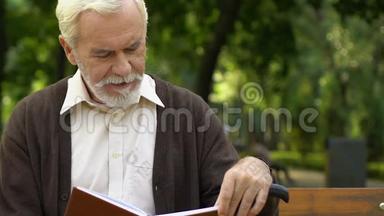 一个<strong>满脸皱纹</strong>的老人坐在长凳上，在公园看书