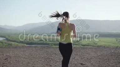 年轻女子健身跑步者在顶部快乐和庆祝成功。 镜头跟着年轻女子的田径比赛