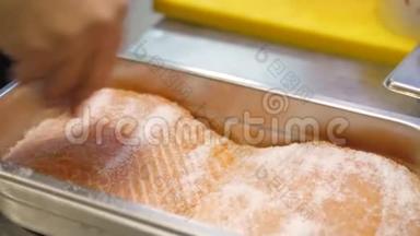 厨师`手腌制鲑鱼鱼片在一个专业的钢盘。