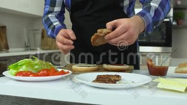 超重的男人在家做汉堡包。胖子把肉排放在面包上。不健康的生活方式，油炸和高<strong>热量</strong>