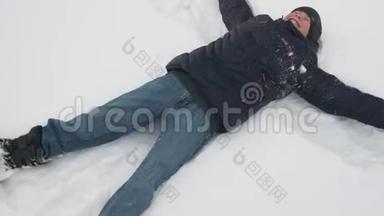 小男孩躺在雪地里，在冬天的森林里玩耍，美丽的风景和雪杉树