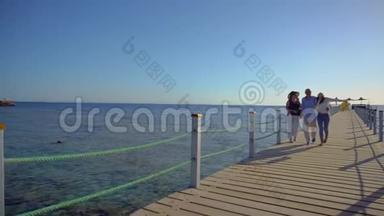 年长夫妇和他们的成年女儿在红海码头散步。 一家人享受假期。