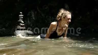 穿着泳衣的年轻女子躺在一条冰冷的河流里，在冰冷的河水中发出情感上的尖叫