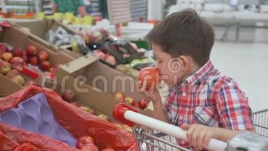 有趣的小男孩在超市的家庭购物中，坐在手推车里的盒子里摘<strong>苹果</strong>