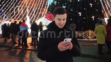 时尚男士在圣诞夜使用手机手机应用程序，街道上装饰着新年晚会
