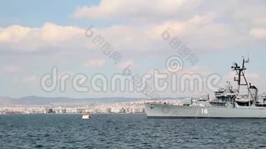希腊塞萨洛尼基市海岸废弃的旧战舰，蓝天上的云彩和住宅建筑