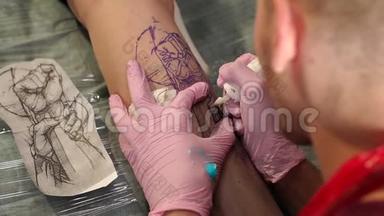 在纹身工作室做纹身的师傅。 男人在女孩腿上做纹身