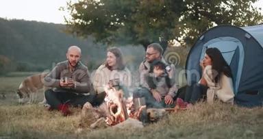 令人惊奇的是，两个家庭在篝火旁开着帐篷野餐，他们<strong>围坐</strong>在一起
