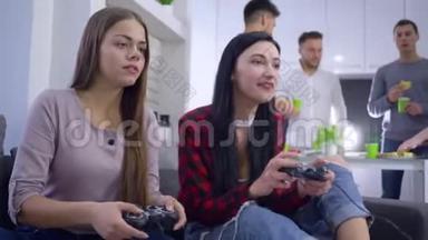 女青少年与女朋友坐在沙发上，坐在家里的公司后台，赢得了视频游戏比赛