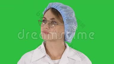 戴眼镜戴帽子的女医生在绿色屏幕<strong>上走来走去</strong>，用彩色键。