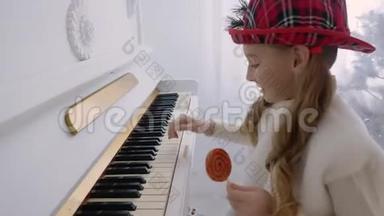 戴着红帽子的滑稽女孩在<strong>弹钢琴</strong>，手里拿着棒棒糖