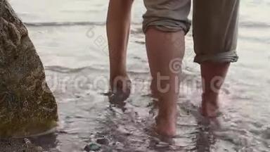 一对夫妇在晴朗的晴天沿着海滩散步。 他们牵手亲吻。 男人和女人的脚在