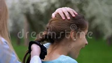 看小女孩的手在玩把女朋友的头发绑在辫子或辫子上，生活方式友好的关系