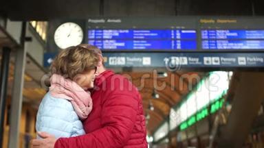 可爱的夫妇在火车站拥抱。 一男一女抱在火车站站台上.. 抚摸