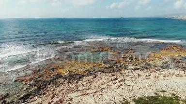 空中拍摄的蓝色海洋和岩石海滩海岸，海浪拍打岩石。塞浦路斯帕福斯海岸线无人机视图