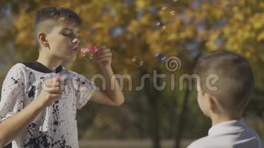 男孩在公园里吹肥皂泡。 孩子们的手在泡泡肥皂泡。 慢动作。