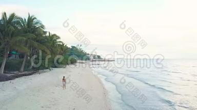 无人机观景女行走在海边的沙滩上。 空中风景女孩在天际线上的热带海滩
