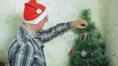 戴圣诞老人帽子的人在圣诞树上挂一个喜庆的球