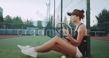 在网球场<strong>上</strong>，<strong>一个</strong>零星的女人准备网球比赛，坐在<strong>地板上放</strong>松。