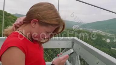 穿着红色T恤的年轻金发女郎在绿色背景下通过智能手机播放视频，屏幕断了