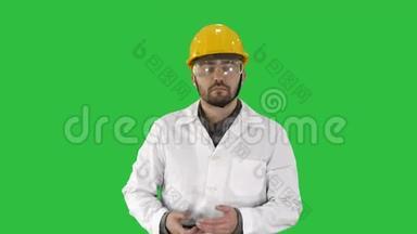 工程师戴着<strong>防</strong>护<strong>眼镜</strong>和帽子走路，在绿色屏幕上拿起电话，Chroma键。