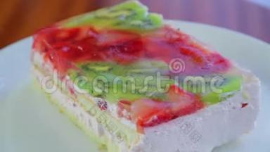 水果蛋糕上有猕猴桃和草莓，果冻放在白色盘子里，旋转成一圈