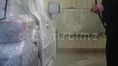 洗车。 洗车机清洗汽车。 洗车工人在汽车上涂上泡沫。 特写镜头。